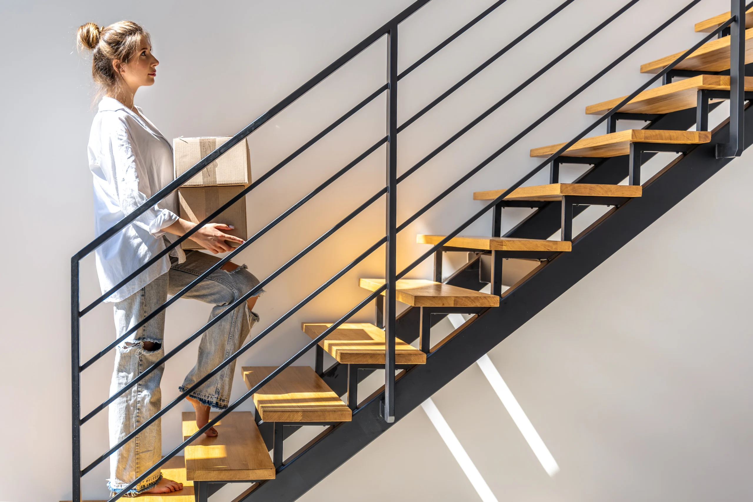 young-woman-with-boxes-walking-up-stairs-home-moving-day